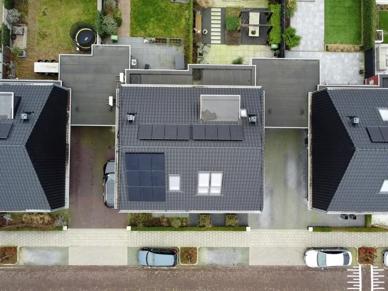 Vista aérea de telhados residenciais com painéis solares e janelas de telhado VELUX. 