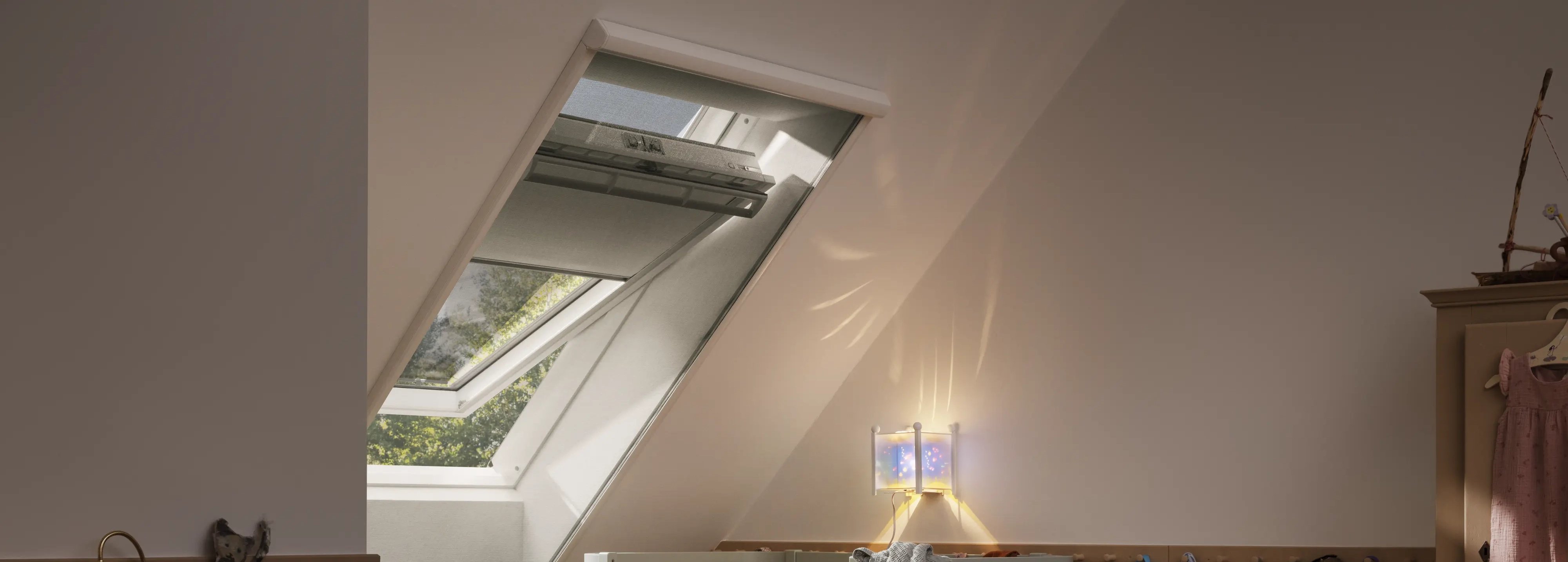 Attic kids room with sloped ceiling and VELUX roof window, cozy decor.