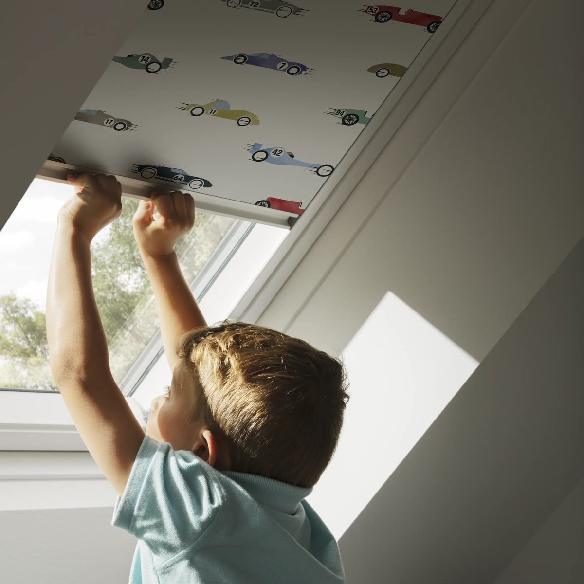 Child adjusting blind on VELUX roof window in attic room.