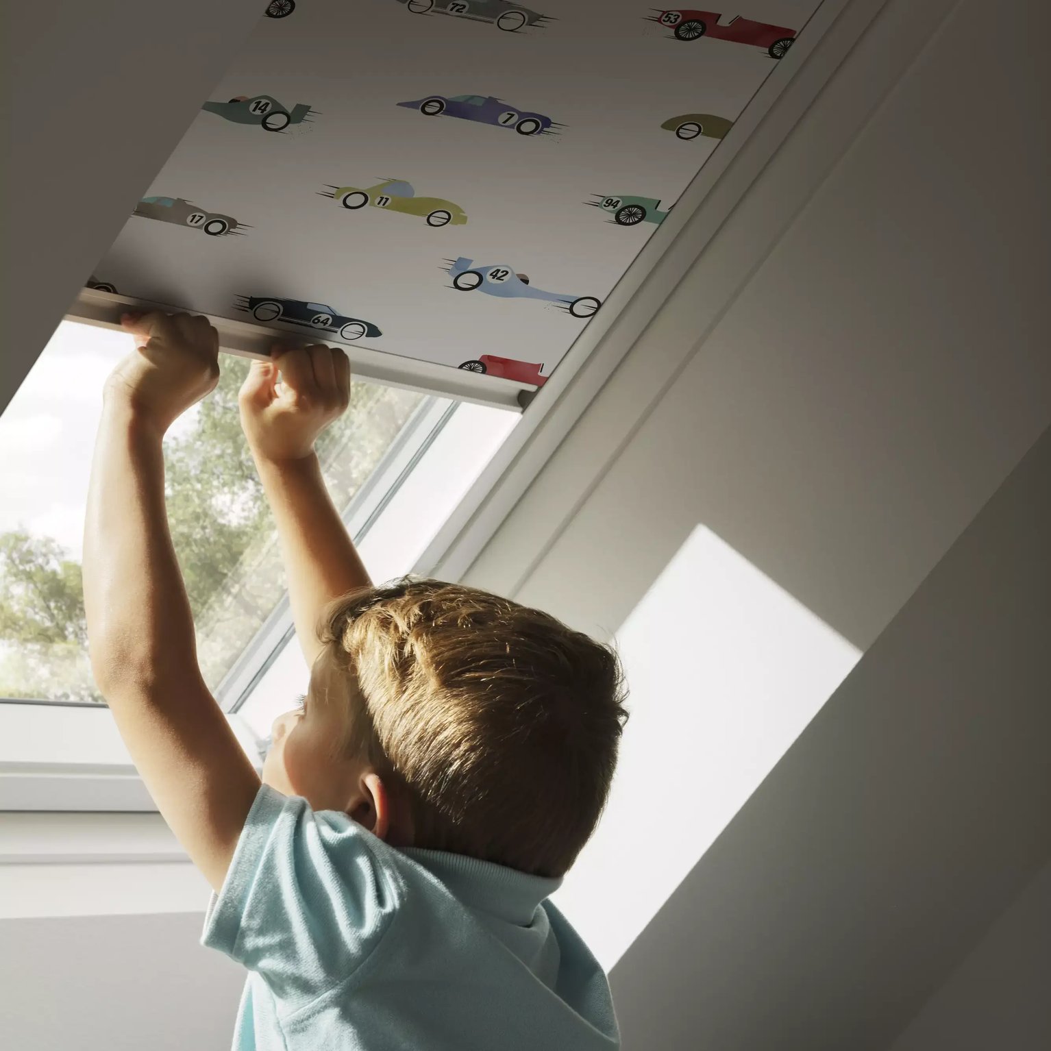 Child adjusting blind on VELUX roof window in attic room.