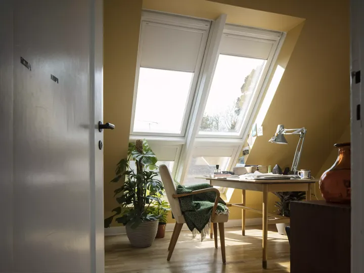 Holz-Schreibtisch steht unter Dachfenster-Kombination mit Sonnenschutz im Arbeitszimmer mit Dachschräge | VELUX Magazin