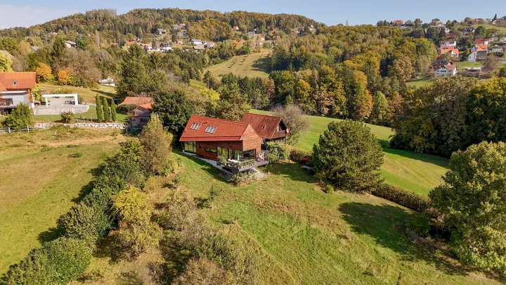 Luftaufnahme eines hölzernen Einfamilienhauses umgeben von Grün in ländlicher Umgebung.