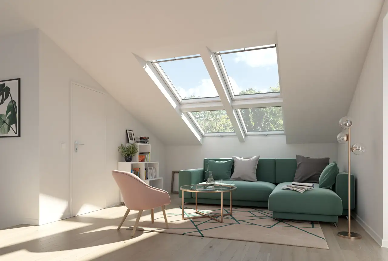 Soggiorno in mansarda con divano verde salvia, poltrona rosa tenue e due grandi finestre per tetti VELUX 