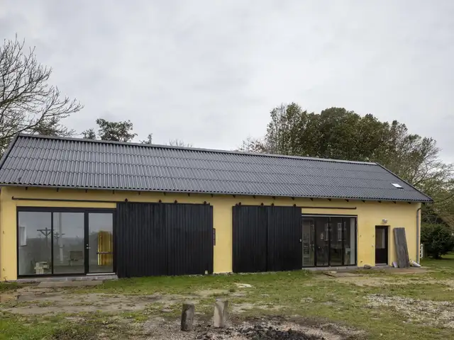 Moderniseret lade med nyt, holdbart eternittag og store glaspartier, der åbner op til naturen