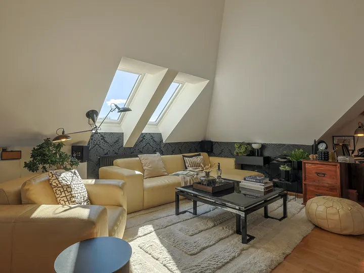 Ausgebauter Dachboden dient als Wohnzimmer, das mit hellen Ledermöbeln und dunklen Akzenten eingerichtet ist | VELUX Magazin