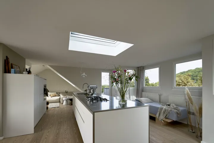 Moderne Küche mit VELUX Dachflächenfenster und angrenzendem Schlafbereich mit Blick ins Grüne.