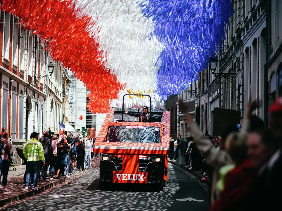 Ulična parada tovornjakov VELUX in pisanimi okraski med Tour de France 2025.
