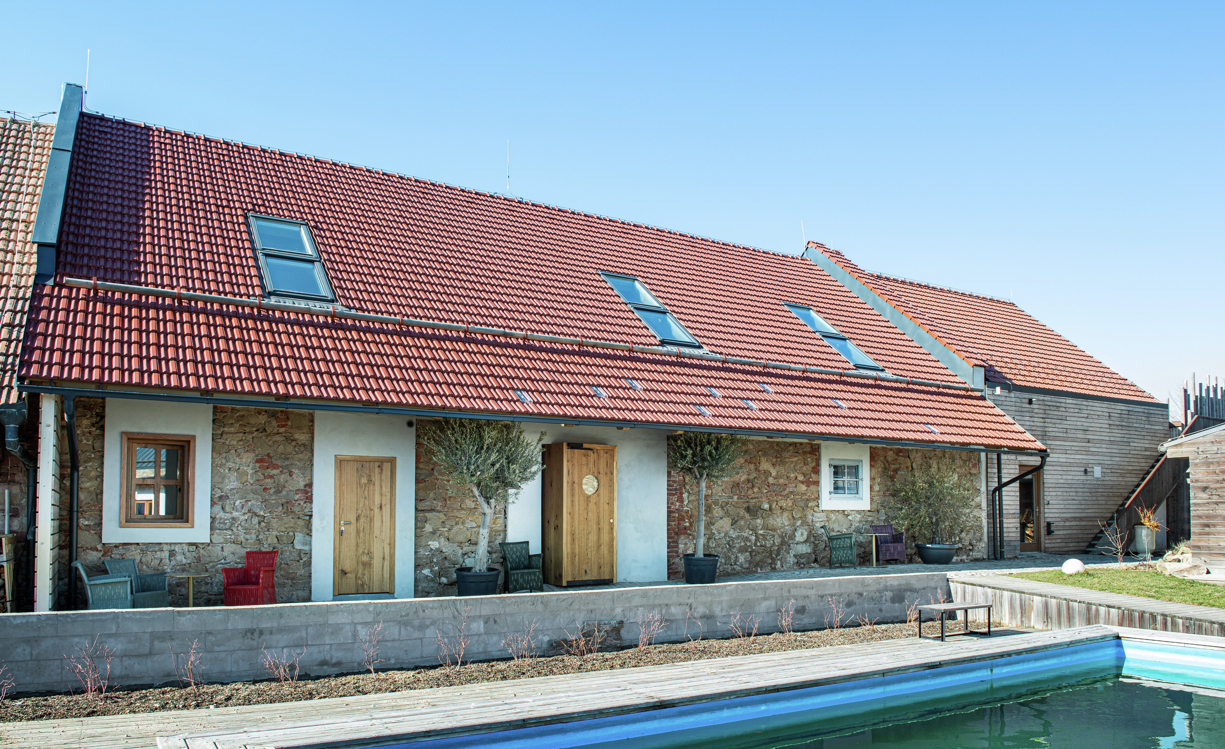 Holiday cottage with red tile roof and VELUX roof windows, garden and pool.