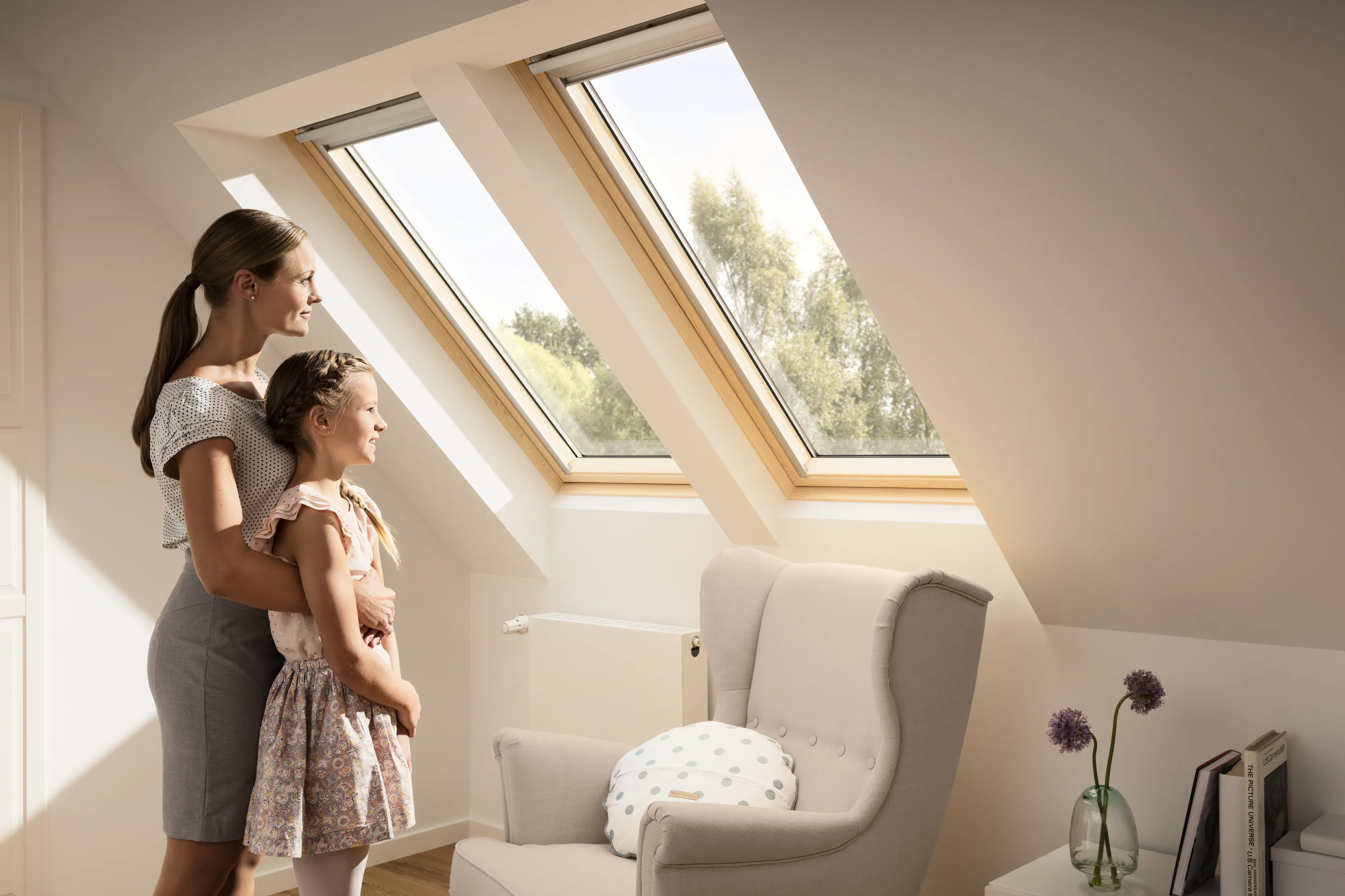 Мансардна кімната з мансардними вікнами VELUX, кріслом та книгами.