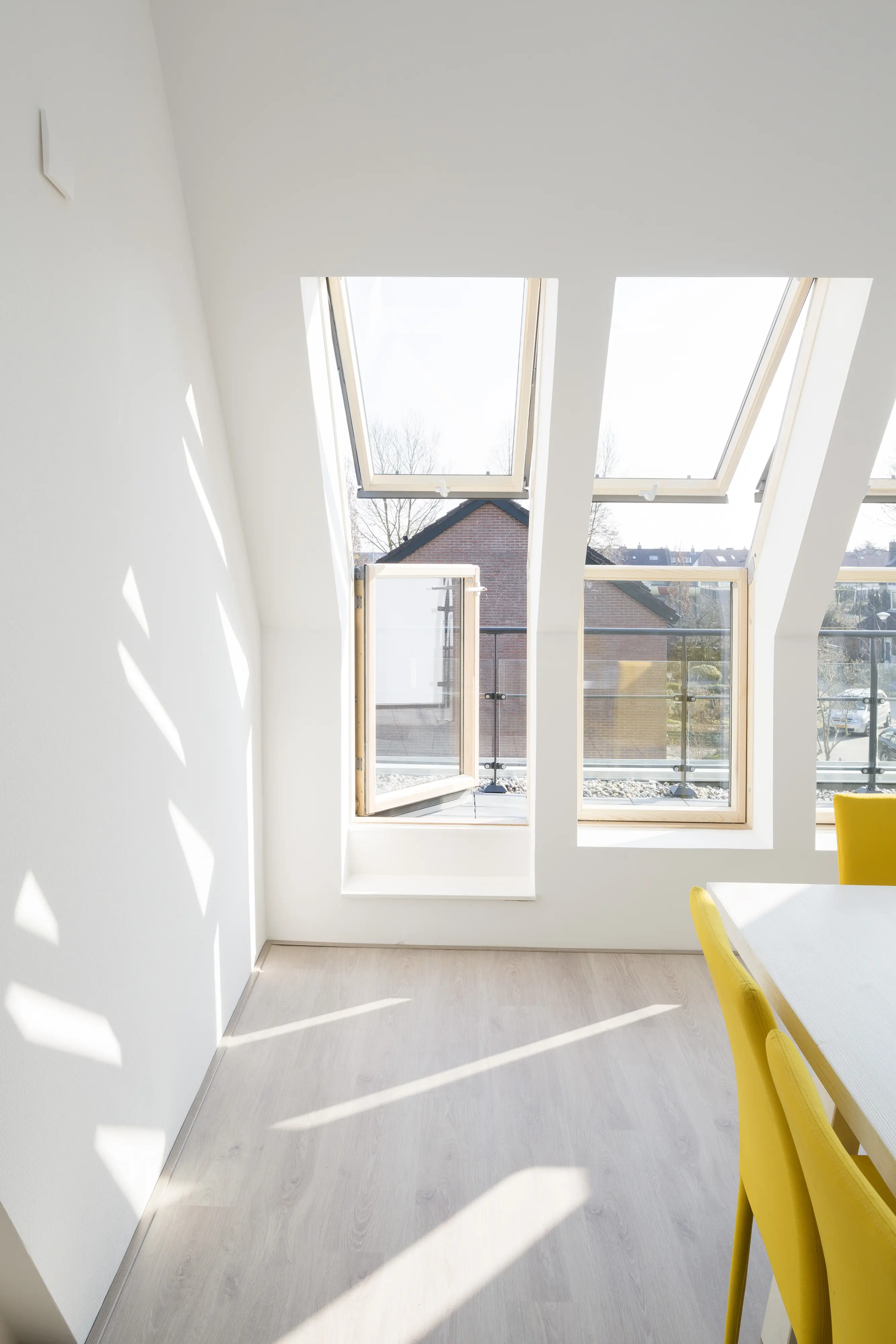 Attic room with sloped ceiling and open VELUX roof windows, bright and airy.