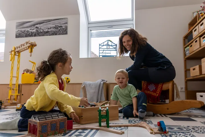 Kinder spielen in einem sonnigen Zimmer mit einem VELUX Dachflächenfenster und lebendigen Spielzeugen.