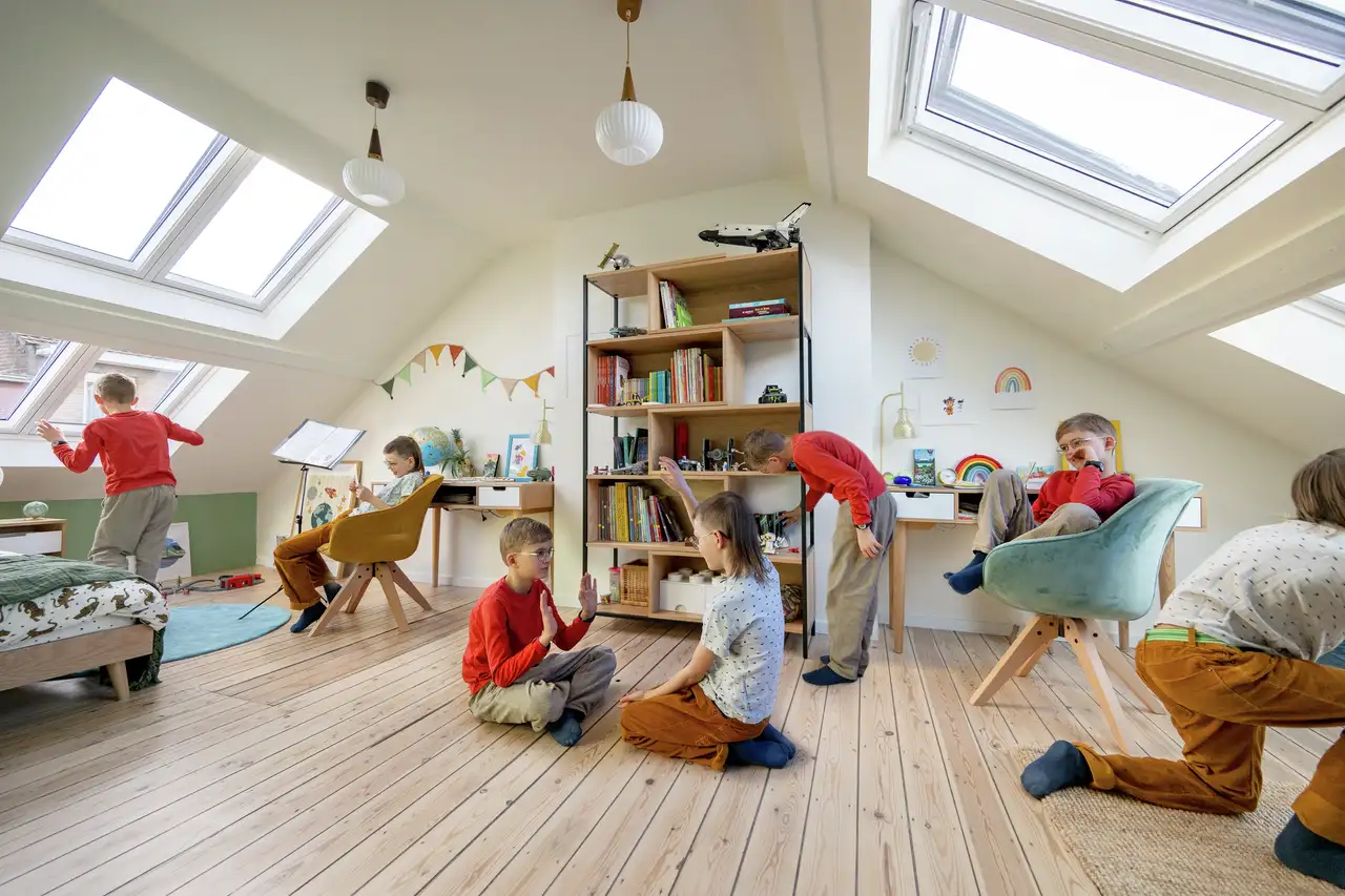 Zolder met zichtbare houten balken, ingericht als speelruimte voor kinderen.