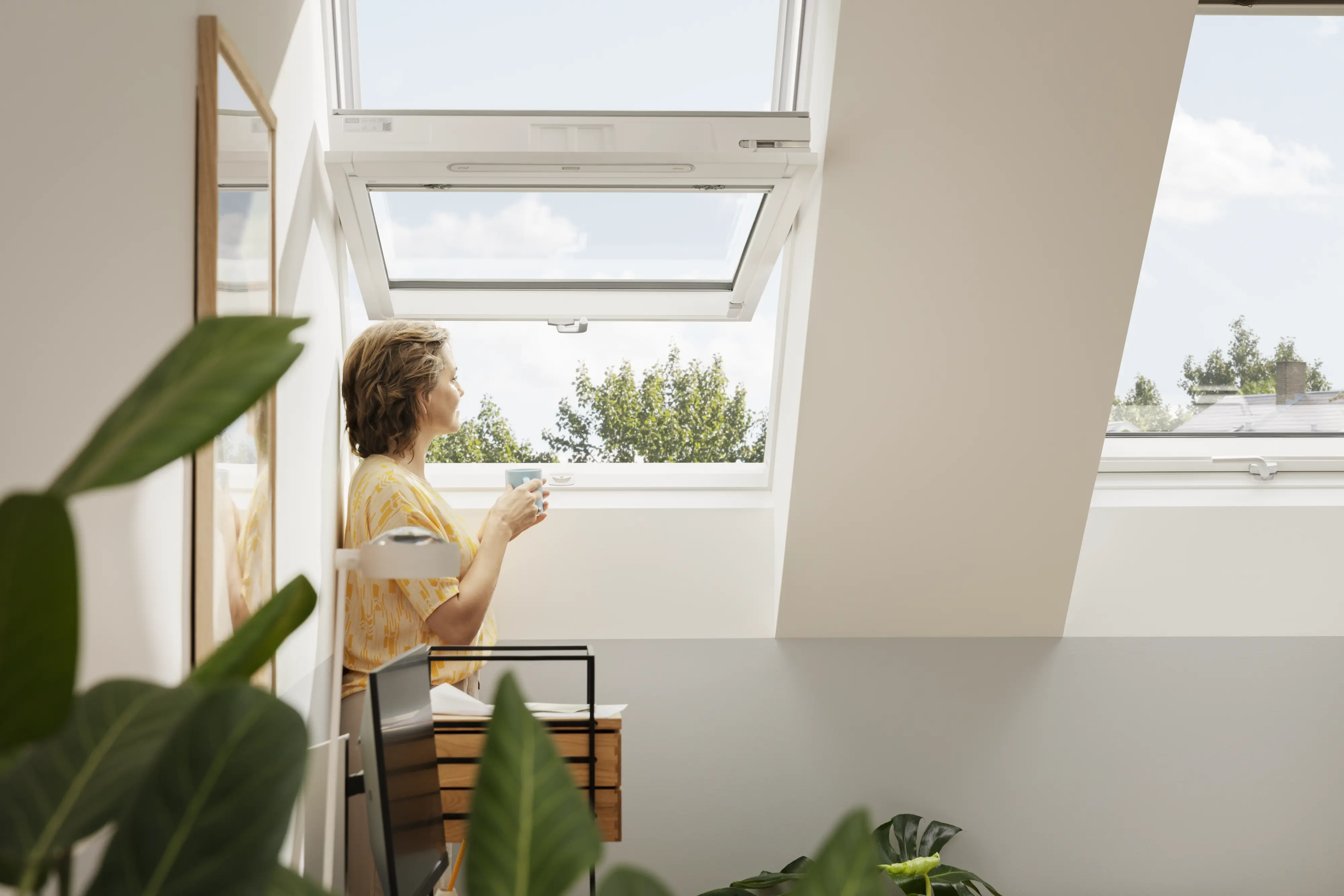 Potkrovlje s otvorenim VELUX krovnim prozorom, prirodnim svjetlom i biljkama.