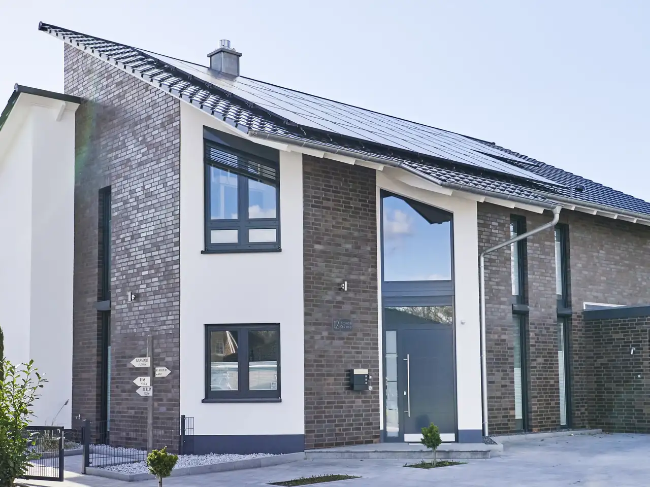 Modernes Haus mit dunklem Klinker und weissen Betonwänden gekennzeichnet durch ein Pultdach | VELUX Magazin