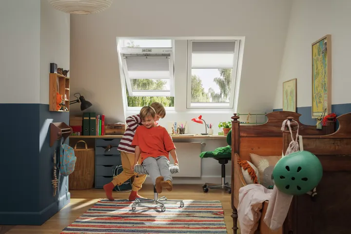 Kinder spielen im hellen Kinderzimmer unter großen Dachfenstern | VELUX Magazin