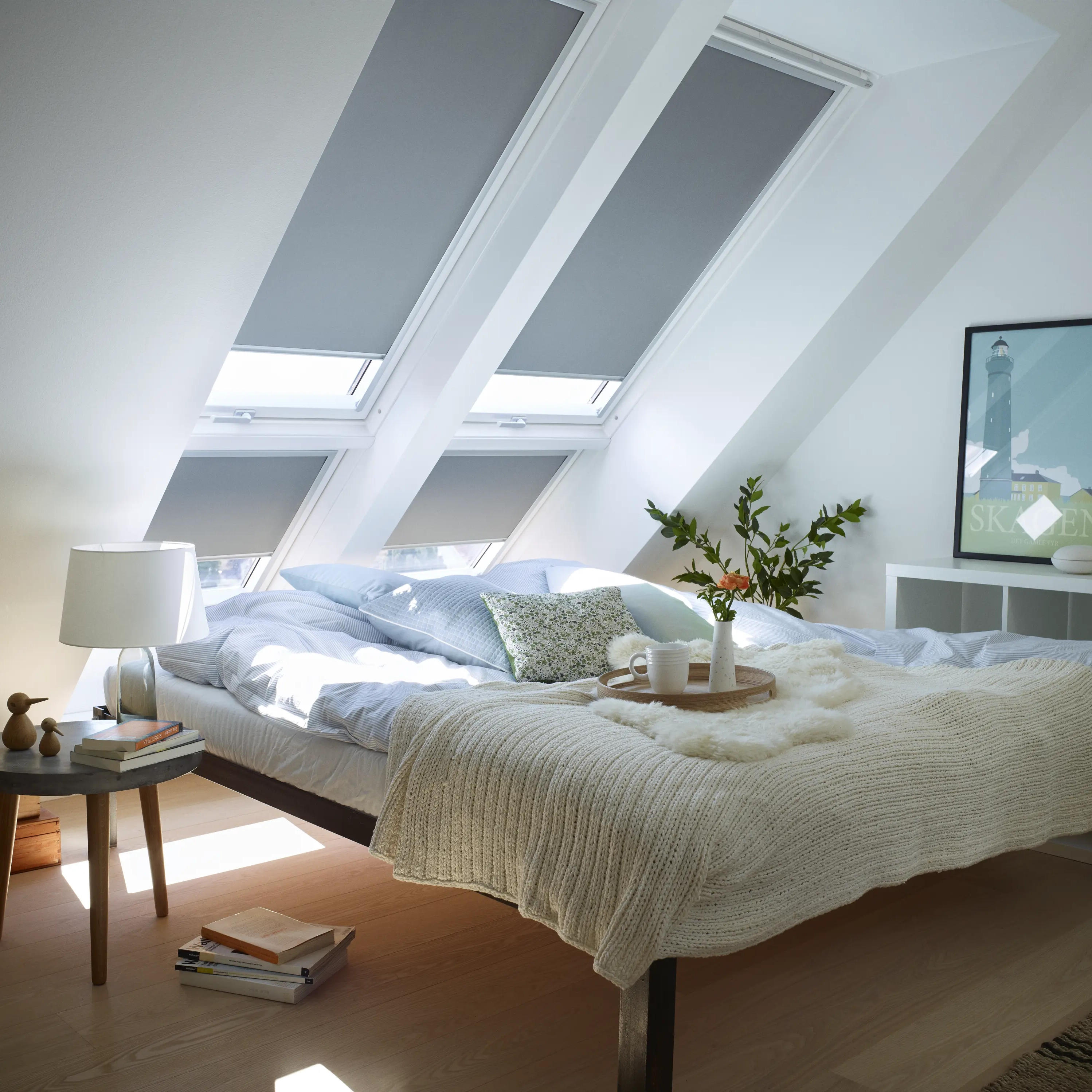 Attic bedroom with sloped ceiling and VELUX roof windows, cozy decor.