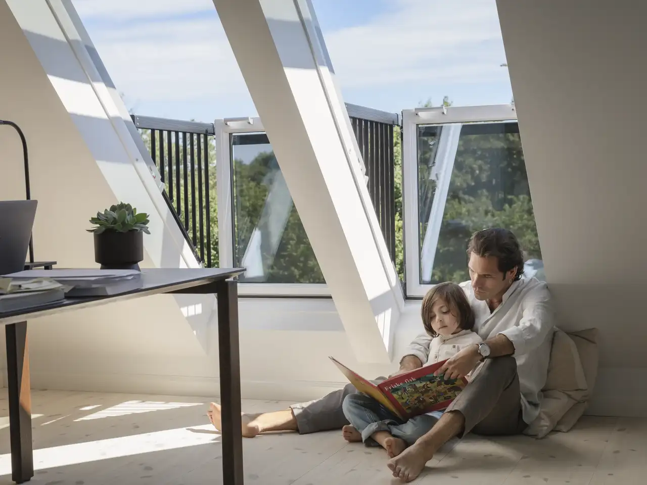 Attic room with sloped ceiling, VELUX roof window open, reading area. 