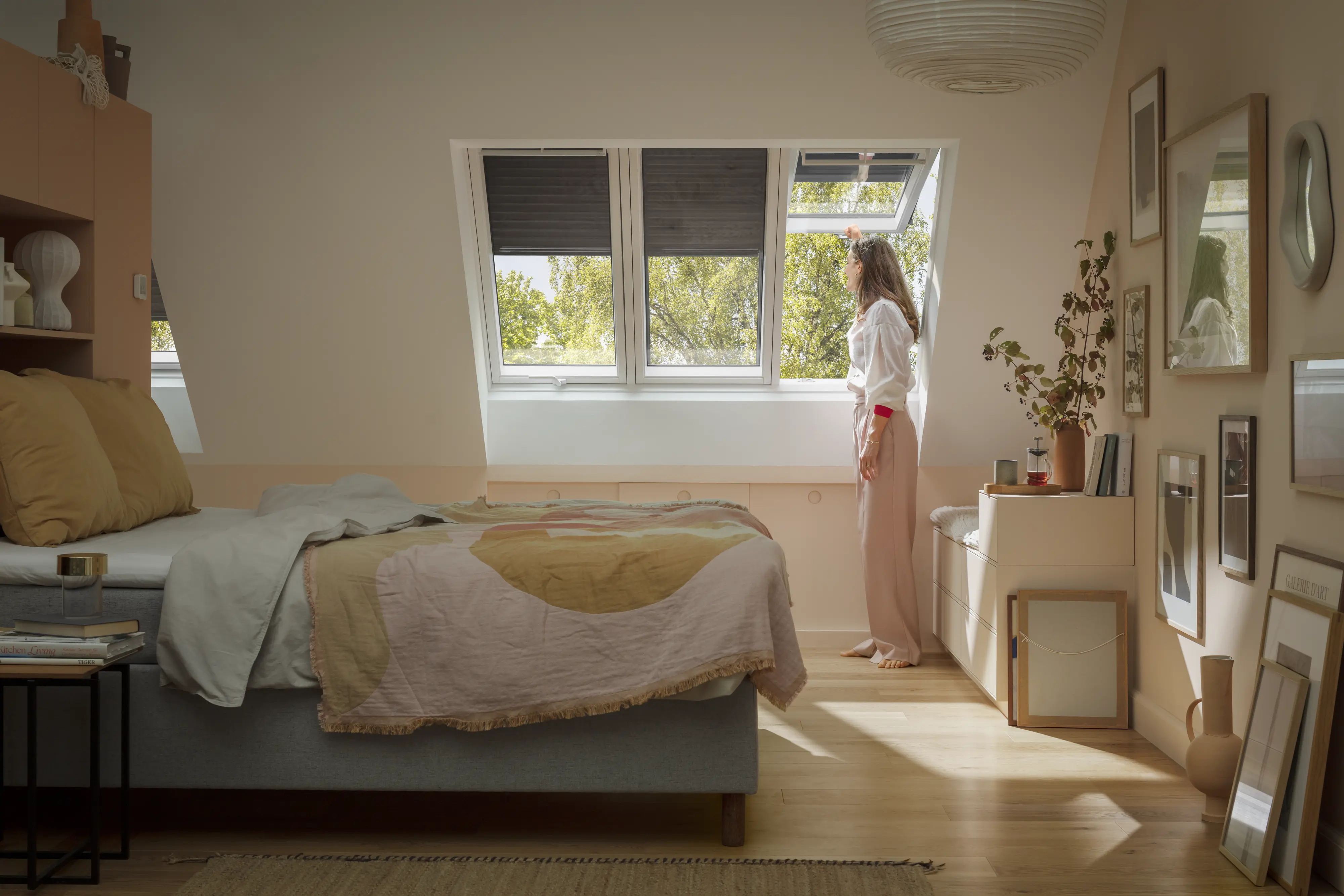 Bēniņu guļamistaba ar slīpiem griestiem un atvērtu VELUX jumta logu, mājīgs interjers.