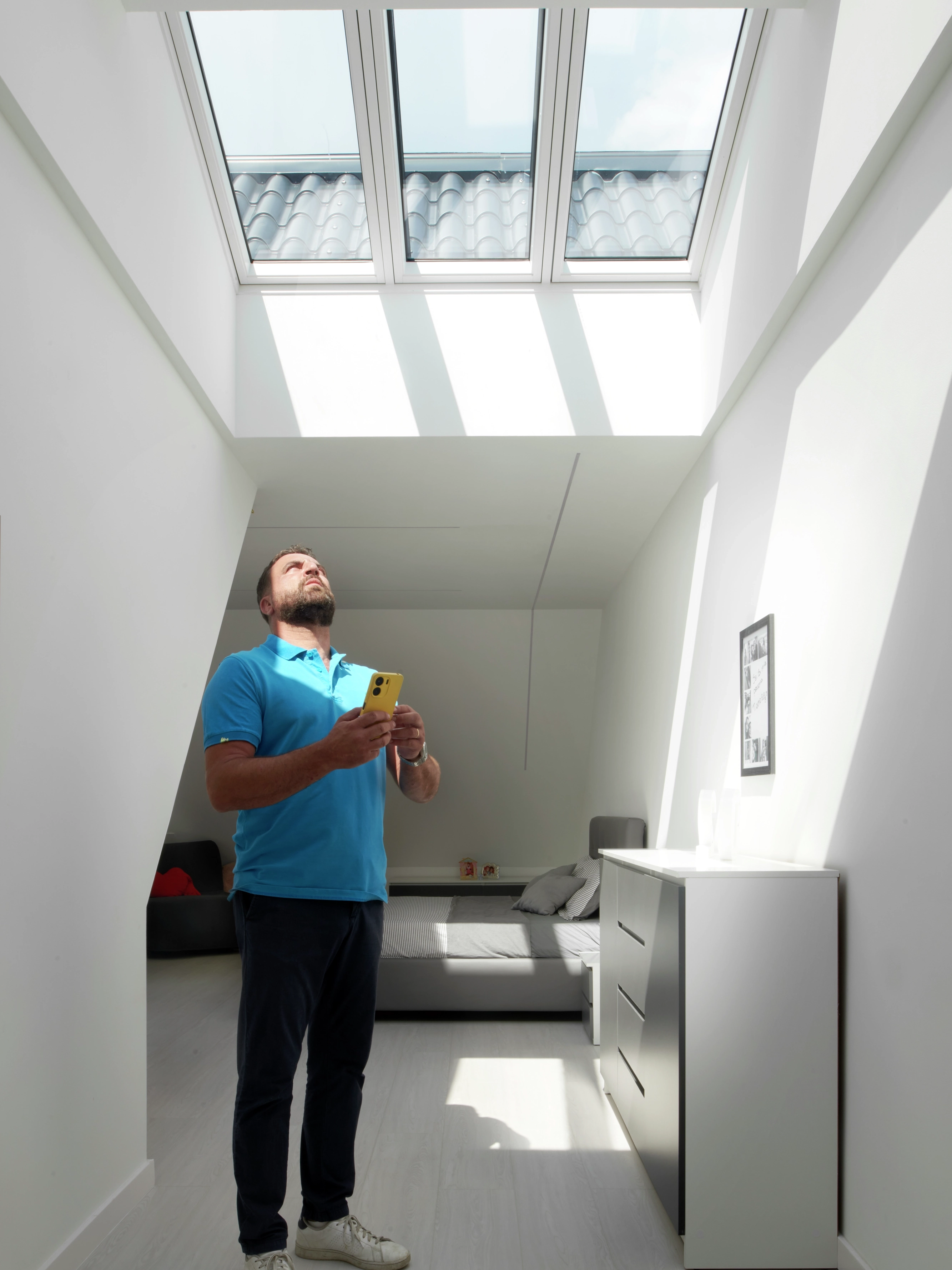Dino osserva il cielo attraverso un pozzo luce trasformato con finestre VELUX, simbolo di ristrutturazione e luce naturale