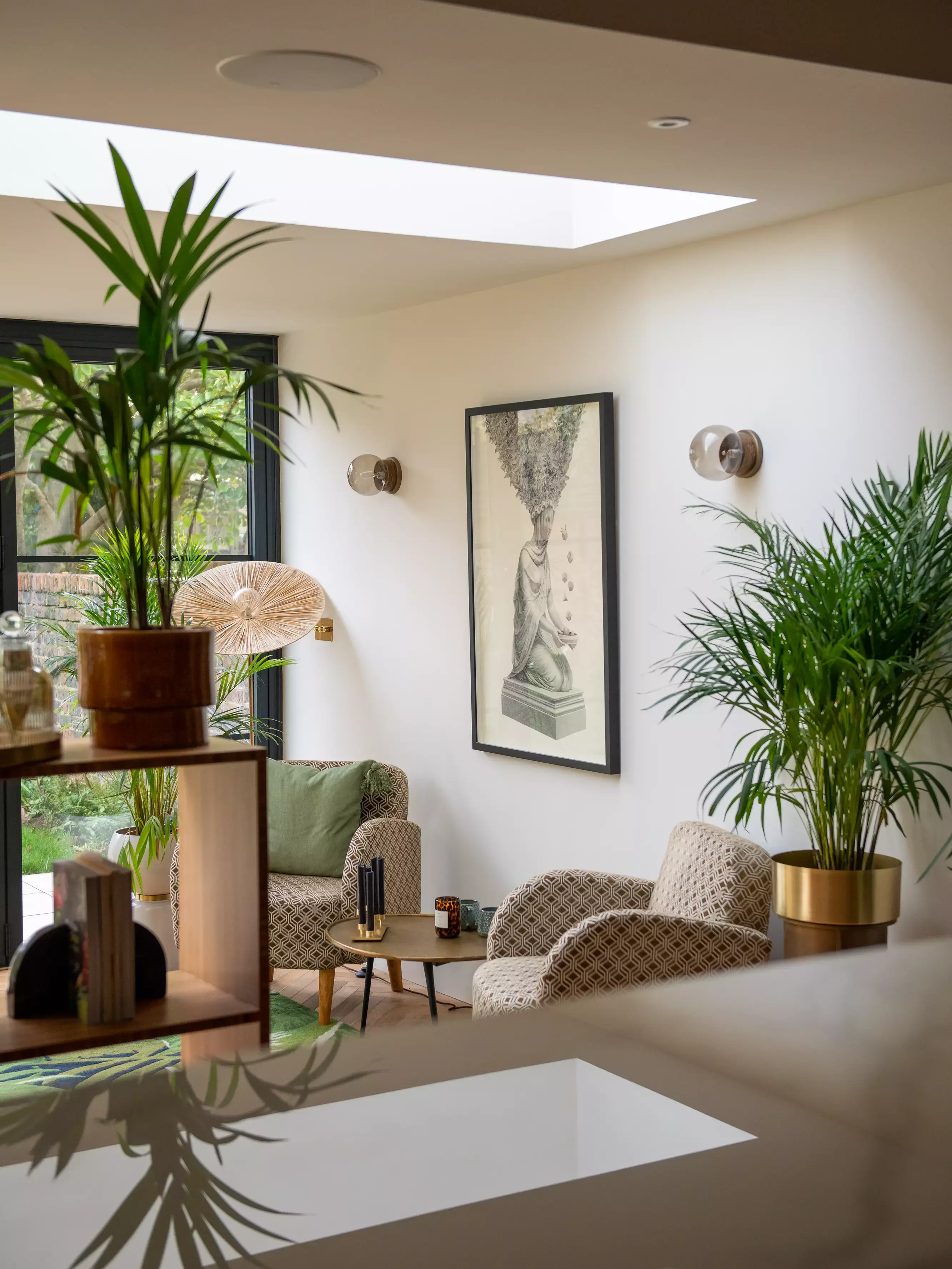 Modern living room with VELUX skylight, patterned armchairs, and indoor plants.