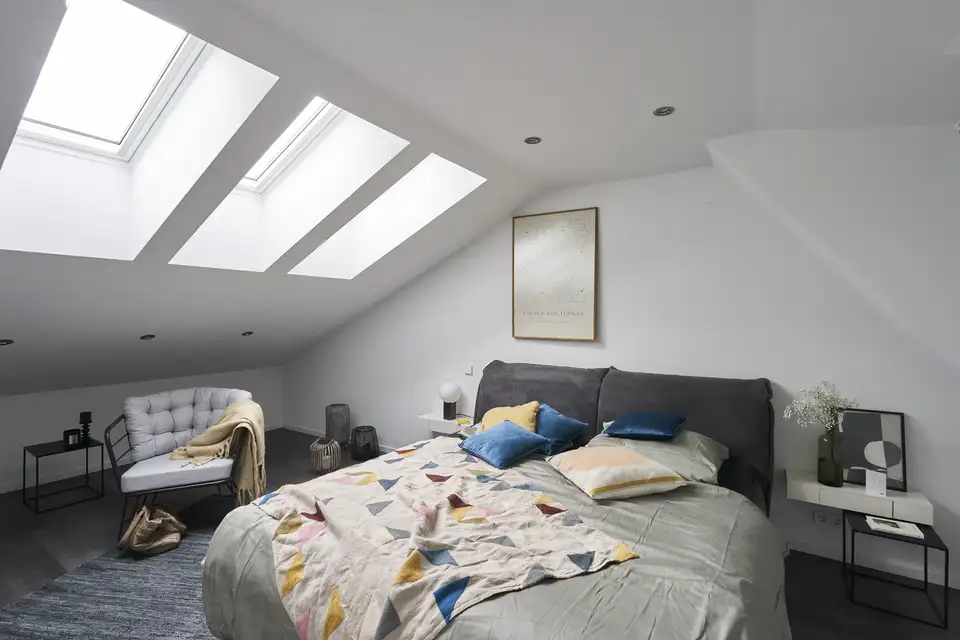 Chambre sous les combles baignée de lumière après l’installation de trois fenêtres de toit VELUX.
