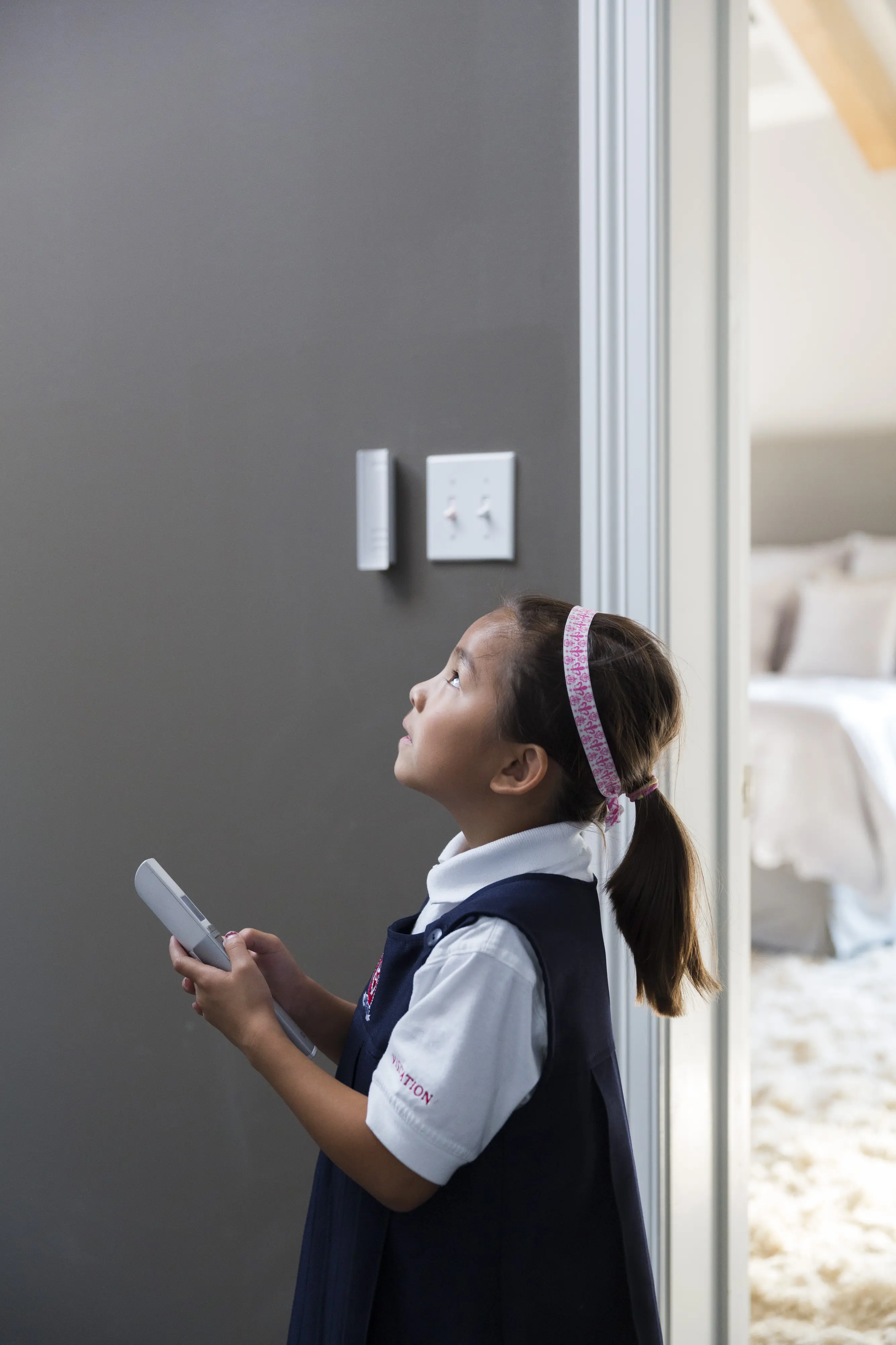 Copil care ține o telecomandă într-un dormitor cu decor confortabil.