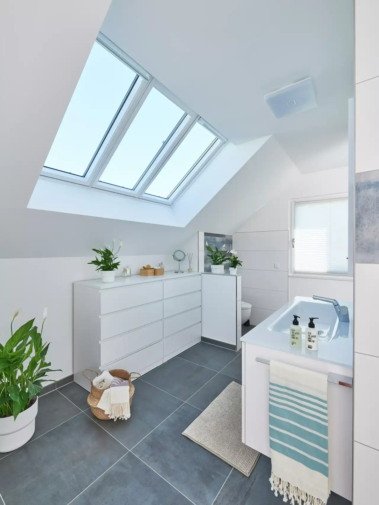 Helles Badezimmer mit blauen Elementen und drei Dachfenstern nebeneinander | VELUX Magazin