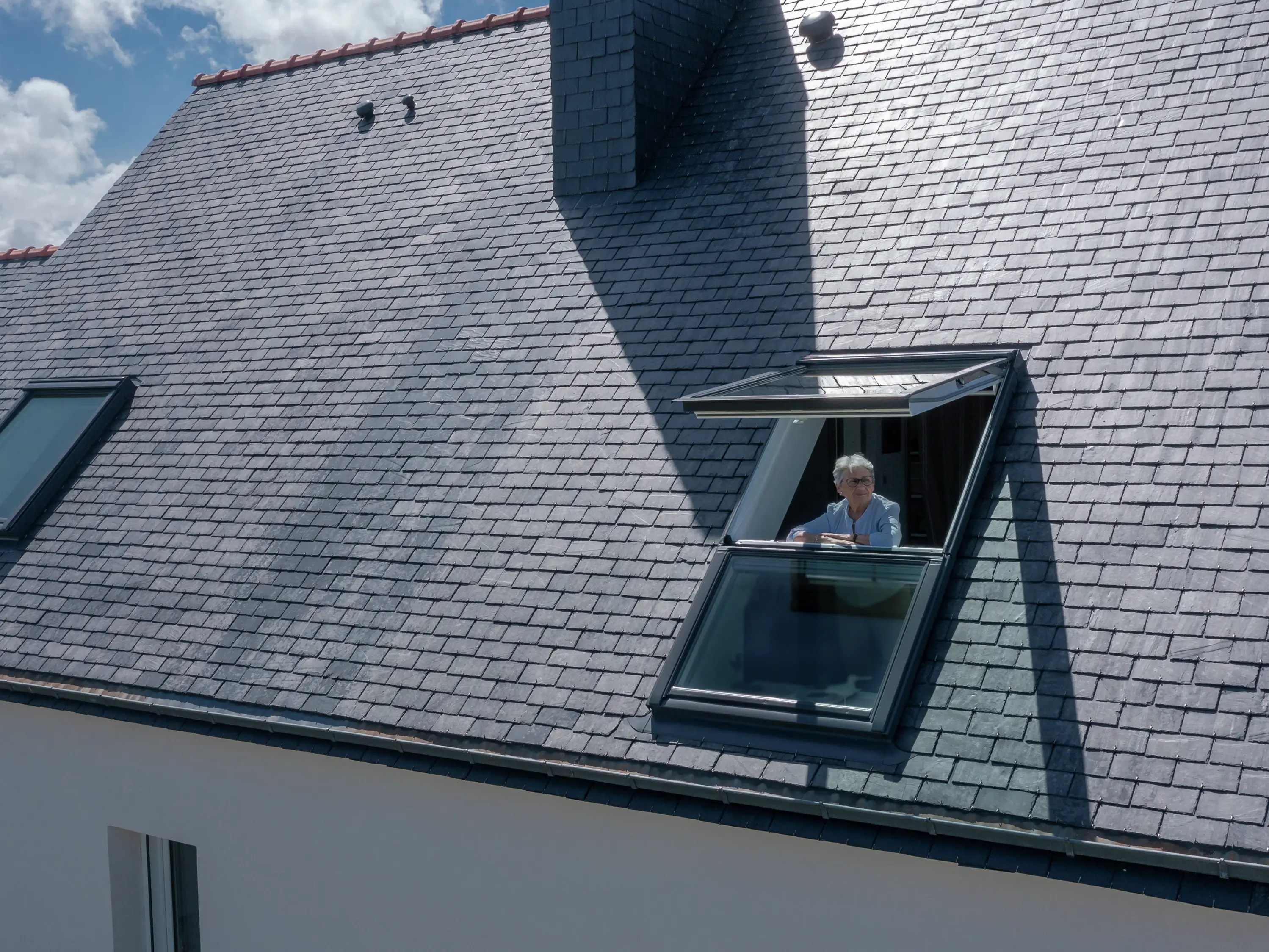Ouvrez la fenêtre de toit VELUX sur un toit en tuiles, éclairant l'espace intérieur.
