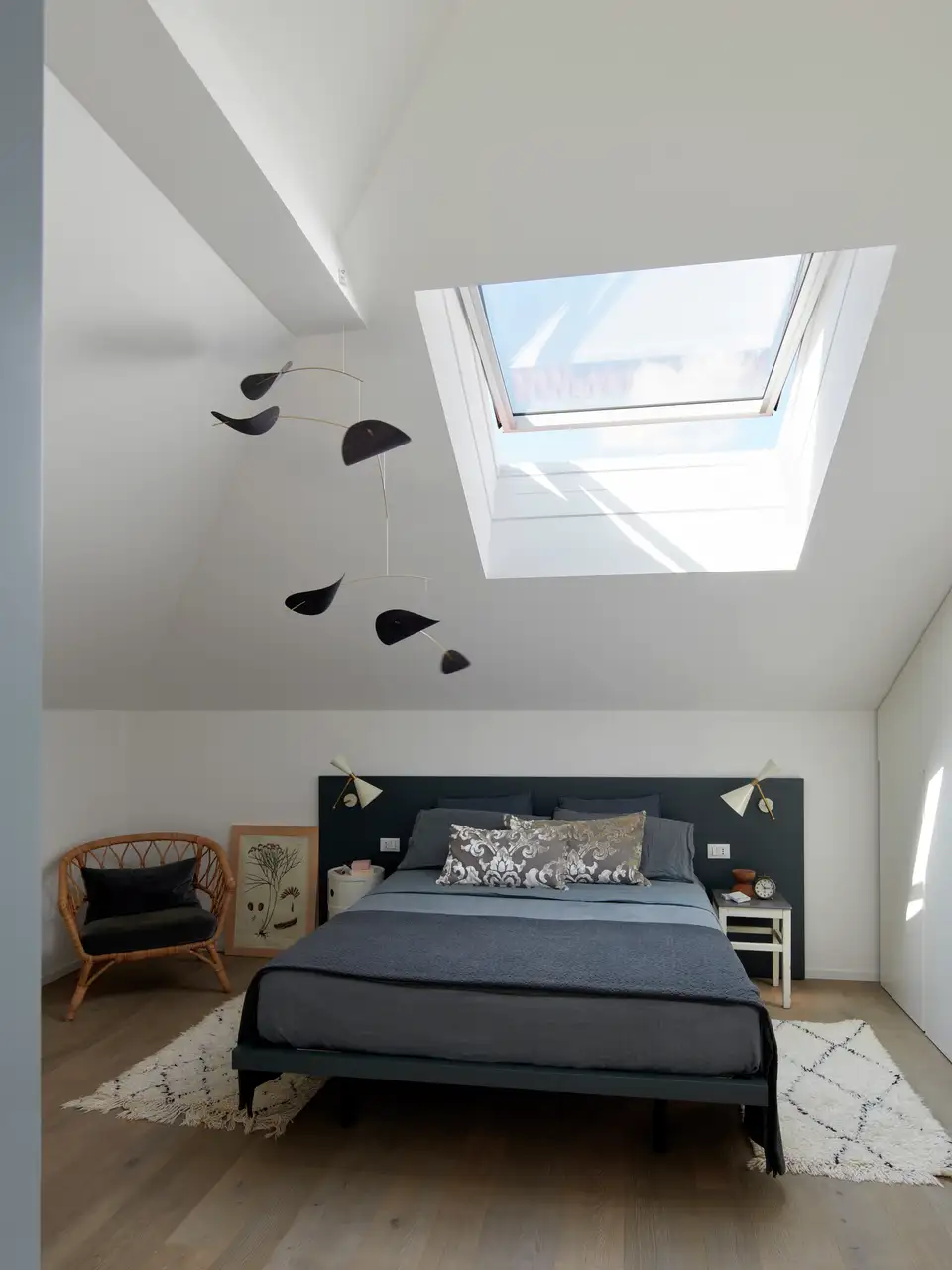Chambre sous les combles avec lit double placé sous une fenêtre de toit.