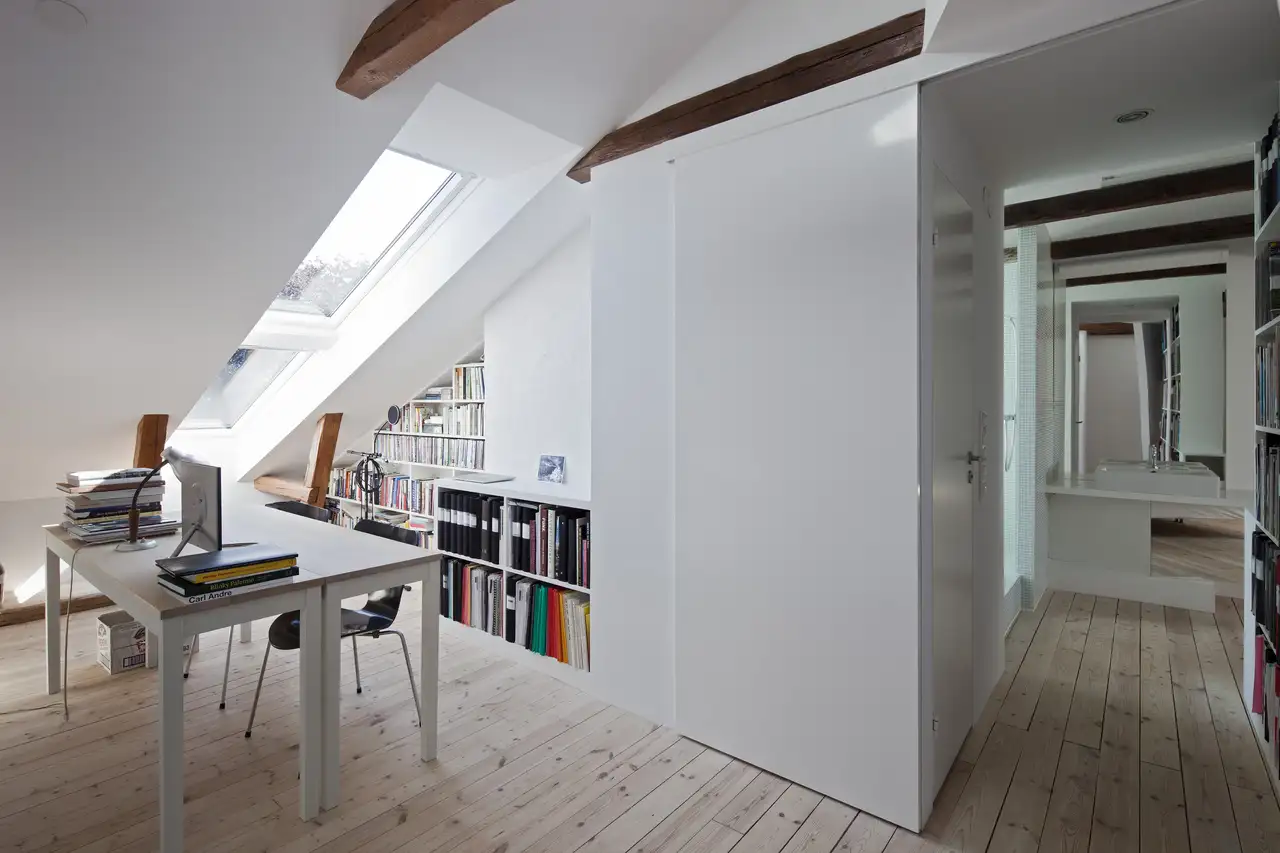 Bureau mansardé avec étagères et lumière naturelle par des fenêtres de toit VELUX 