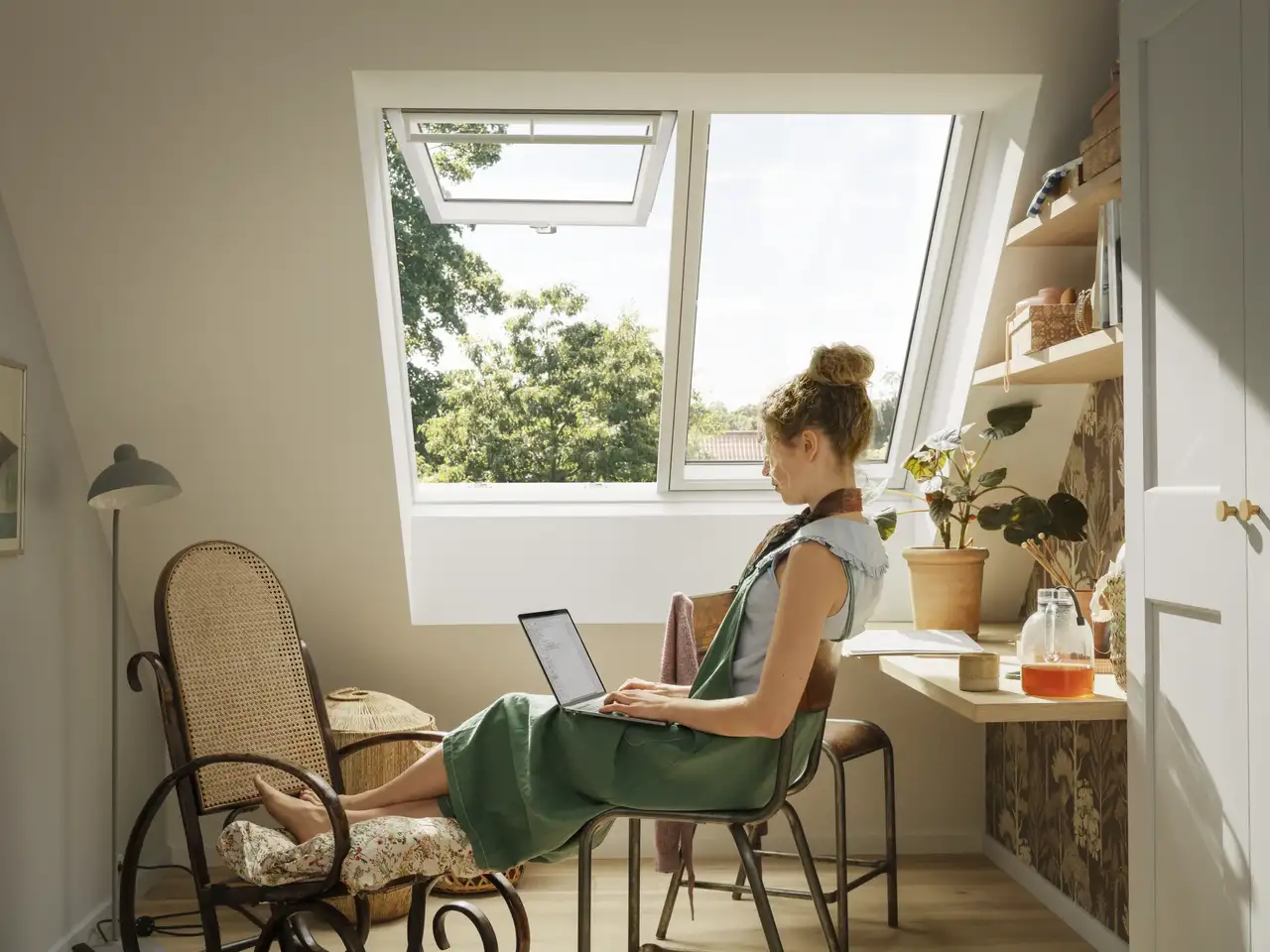 Espace de travail mansardé avec plafond incliné et fenêtre de toit VELUX ouverte.