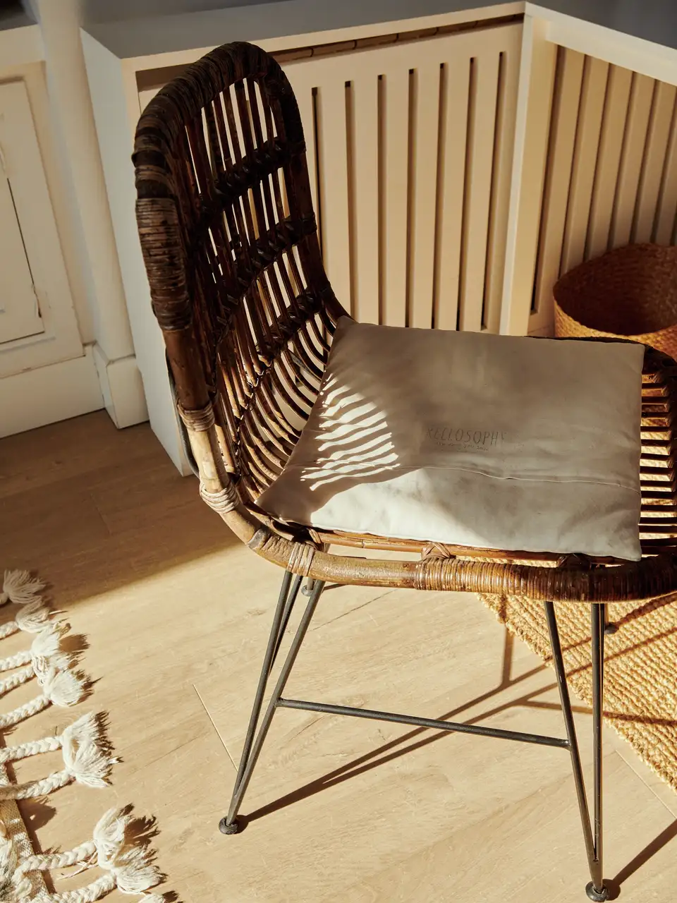 Wicker chair with cushion in a sunlit corner, near radiator cover
