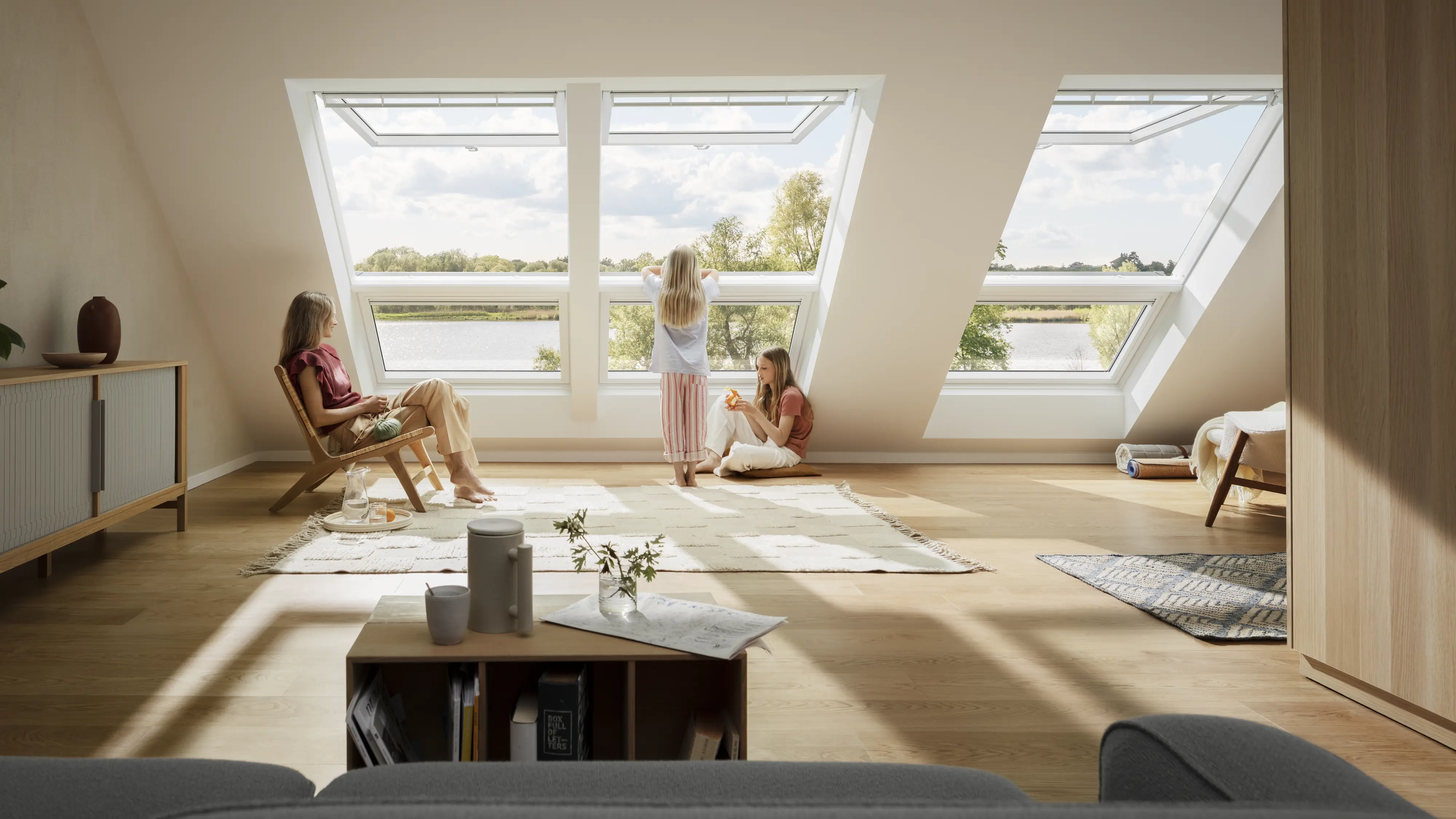 Cameră mansardată cu ferestre de mansardă VELUX deschise, lumină naturală și vedere panoramică.