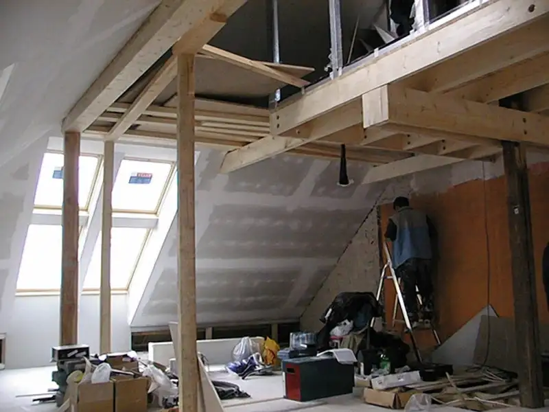 Stavebná scéna pri rekonštrukcii podkrovia s drevenou konštrukciou, zateplením a osadenými strešnými oknami, ktoré zvyšujú množstvo denného svetla. | VELUX