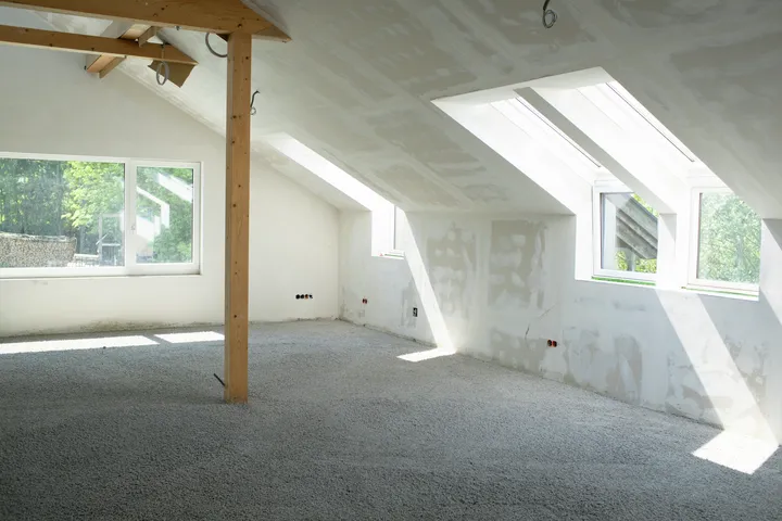 Dachboden bevor Trockenbau mit grauem Teppich und unbehandelten Holzbalken | VELUX Magazin