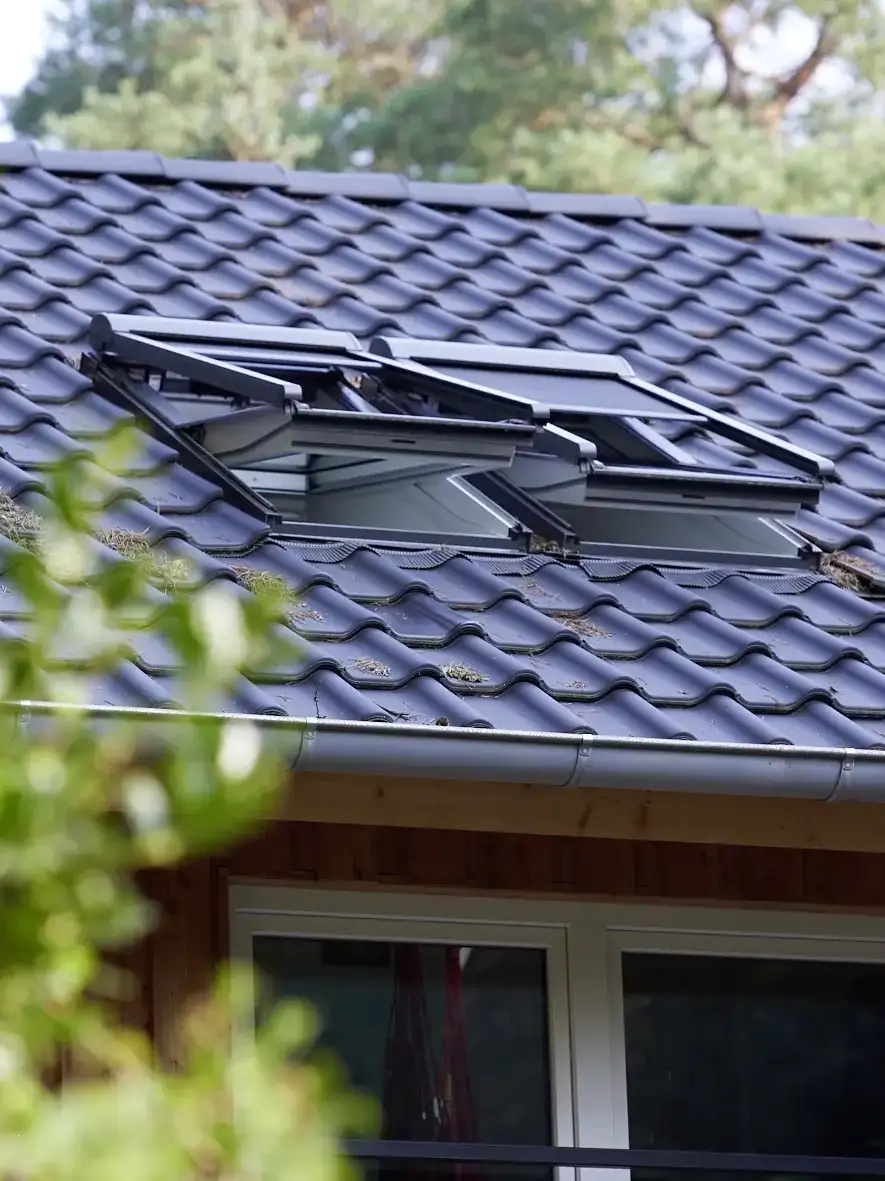 Zwei offene Dachfenster installiert auf Satteldach mit blauen Ziegeln | VELUX Magazin