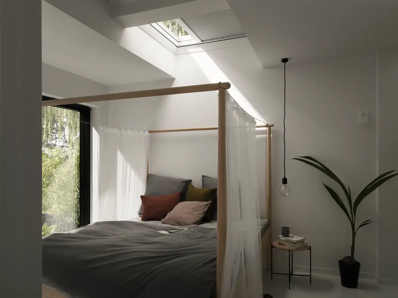 Bedroom with canopy bed under VELUX flat rooflight fitted with blackout pleated blind for better sleep.