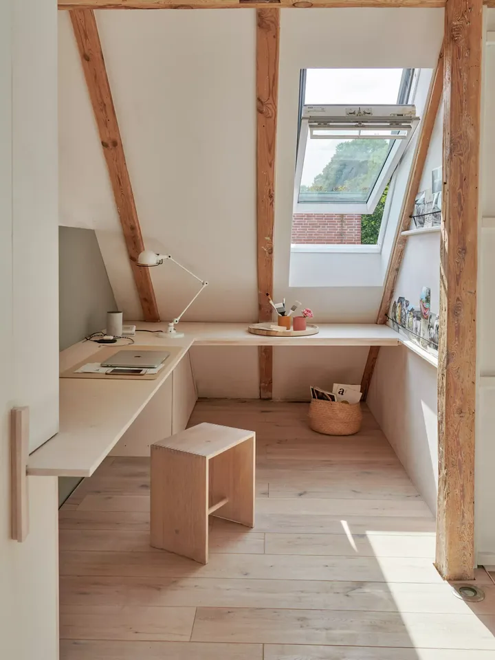 Gemütliches Dachboden-Homeoffice mit VELUX Dachflächenfenster und minimalistischen hölzernen Möbeln.