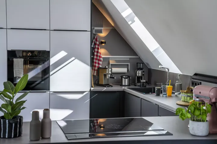 Moderne Küche mit VELUX Dachflächenfenster und glänzenden Schränken.