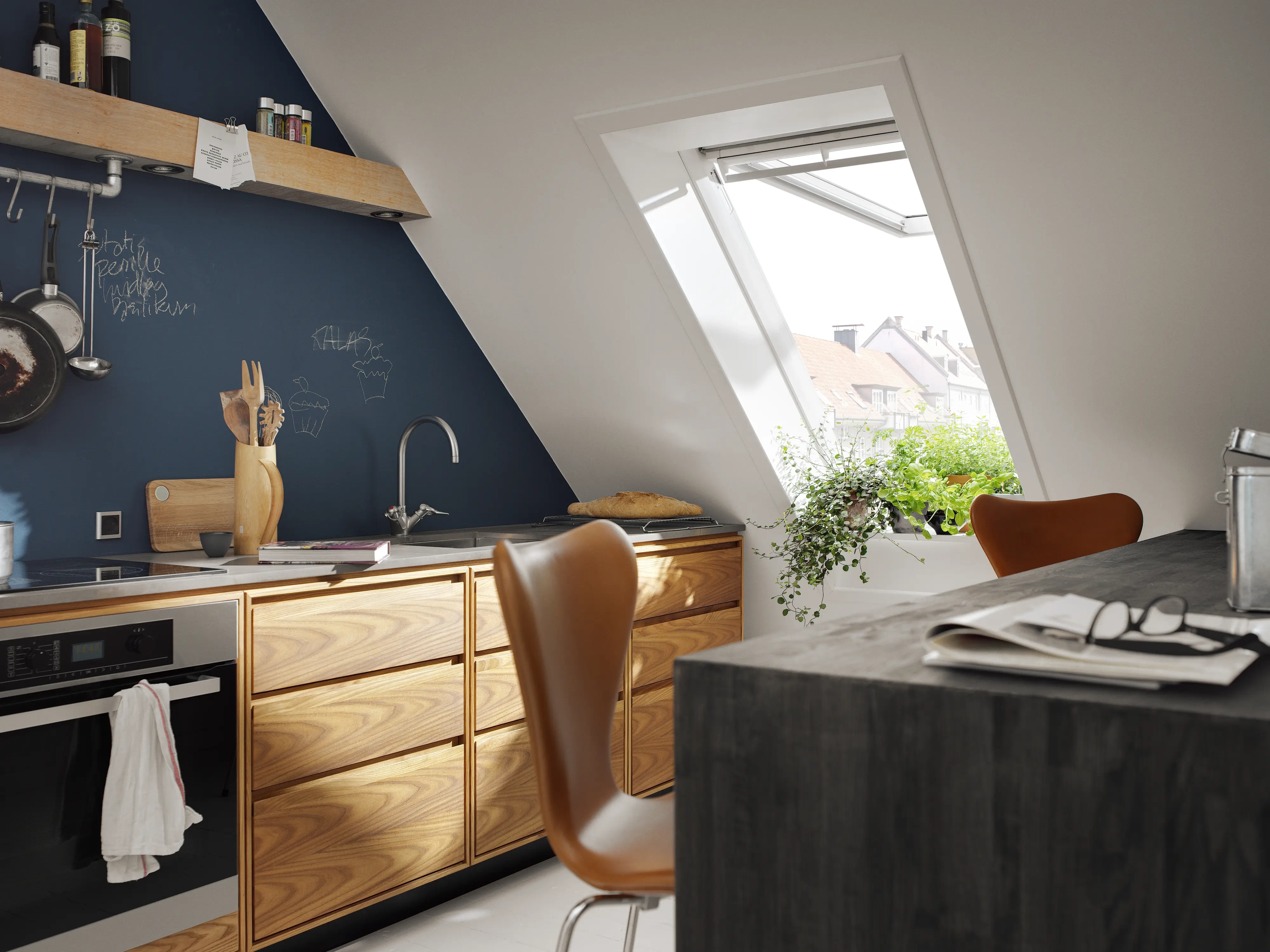 Cucina in mansarda con mobili in legno chiaro e tavolo con sedie
