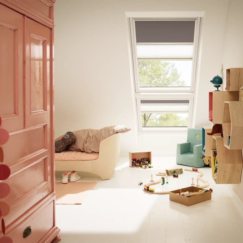 Attic kids room with sloped ceiling and VELUX roof window, playful decor.