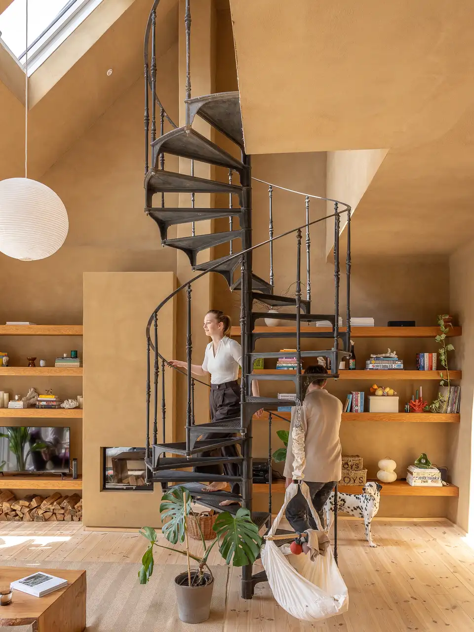 un couple monte un escalier en colimaçon de style industriel dans son salon - VELUX