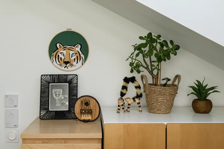 Heimbüro-Ecke mit Tiger-Wandkunst, gestreiftem Spielzeug und grünen Pflanzen.