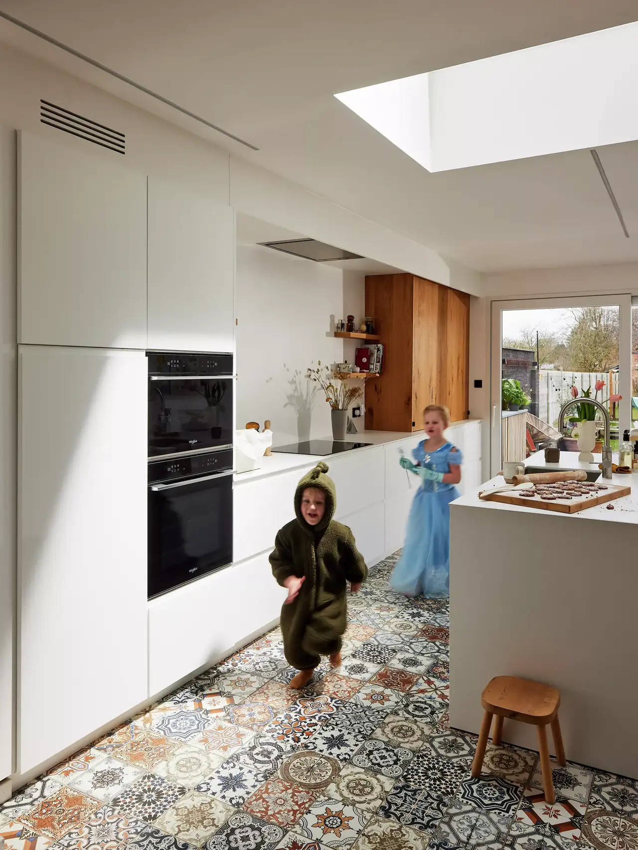 Moderne Küche mit weißen Schränken, gemustertem Boden und natürlichem Licht von VELUX Dachflächenfenstern.