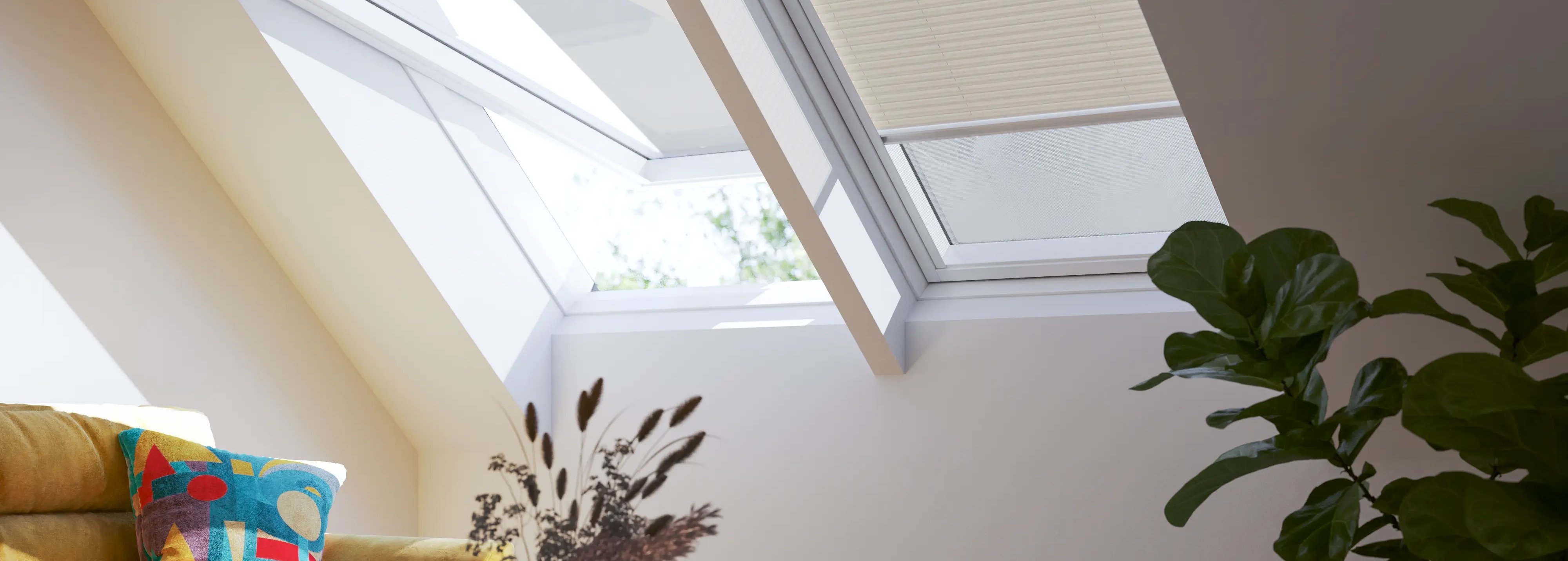 Attic living room with sloped ceiling and VELUX roof windows, cozy decor.