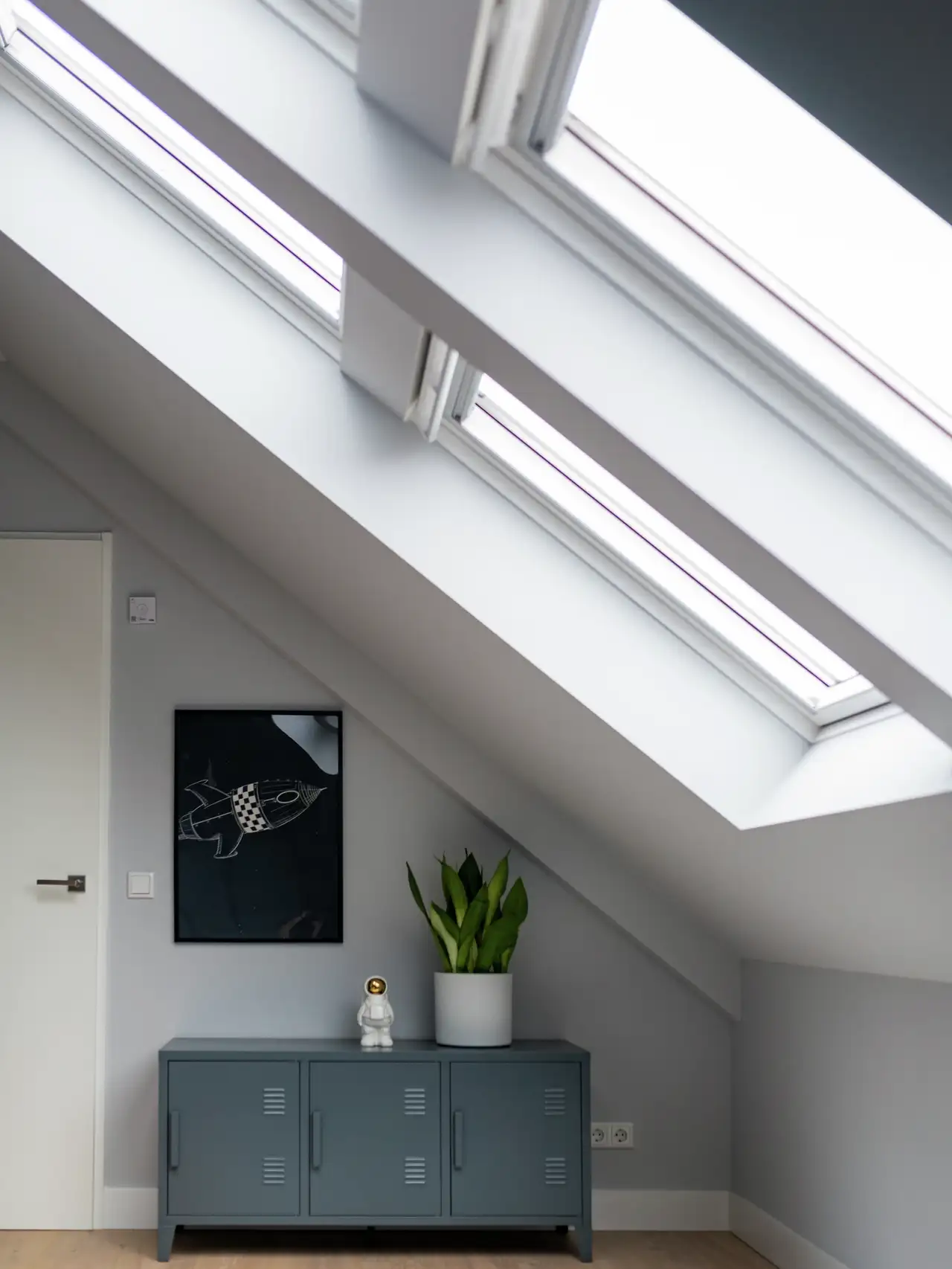 Zolderkamer met schuine plafonds en VELUX dakramen, moderne inrichting.