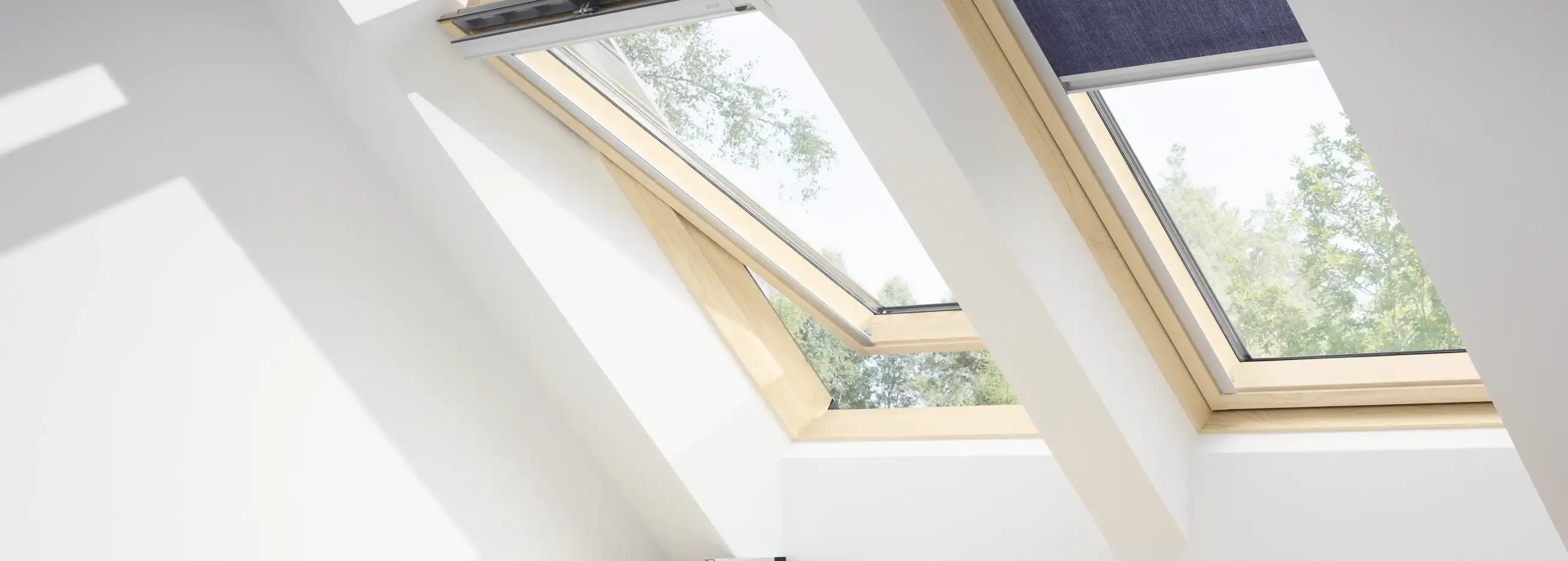 Attic workspace with VELUX roof windows, natural light and greenery view.