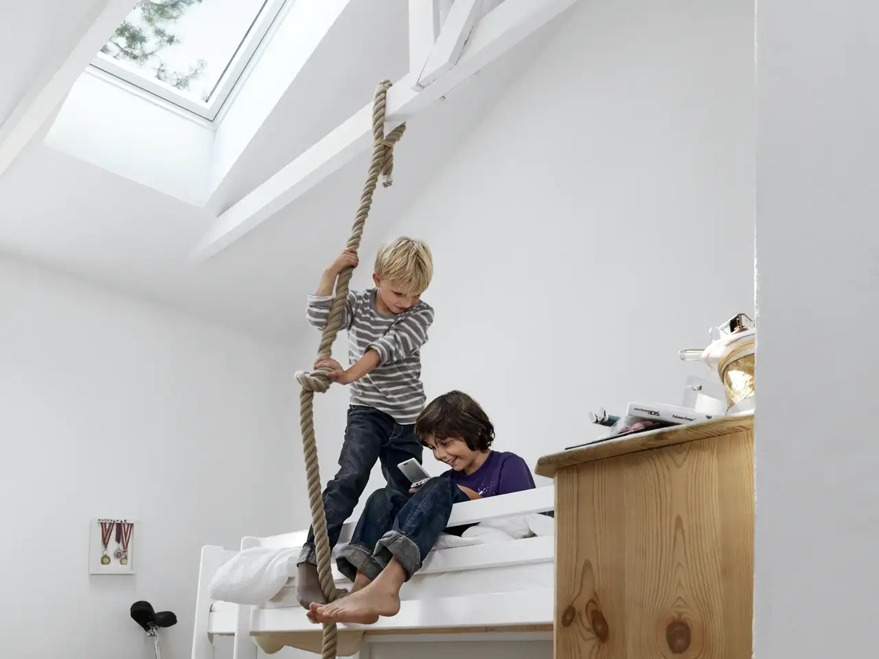 Due bambini che giocano sul loro letto rialzato con protezione anticaduta | Rivista VELUX