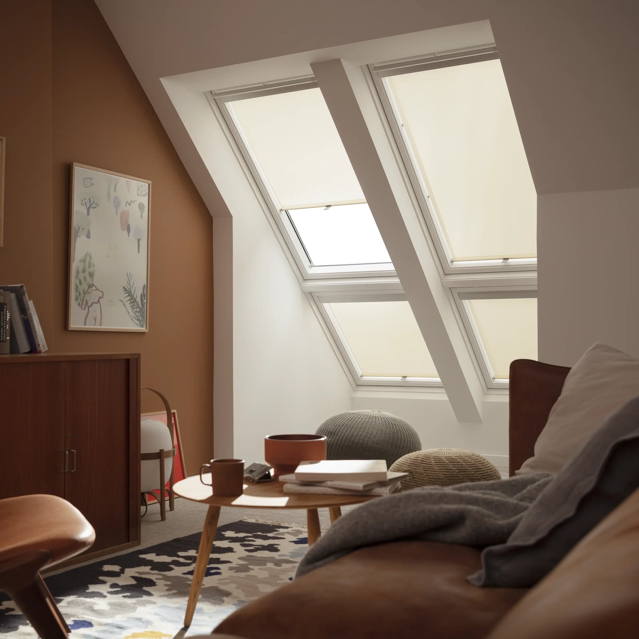 Attic living room with sloped ceiling and VELUX roof windows, cozy decor.