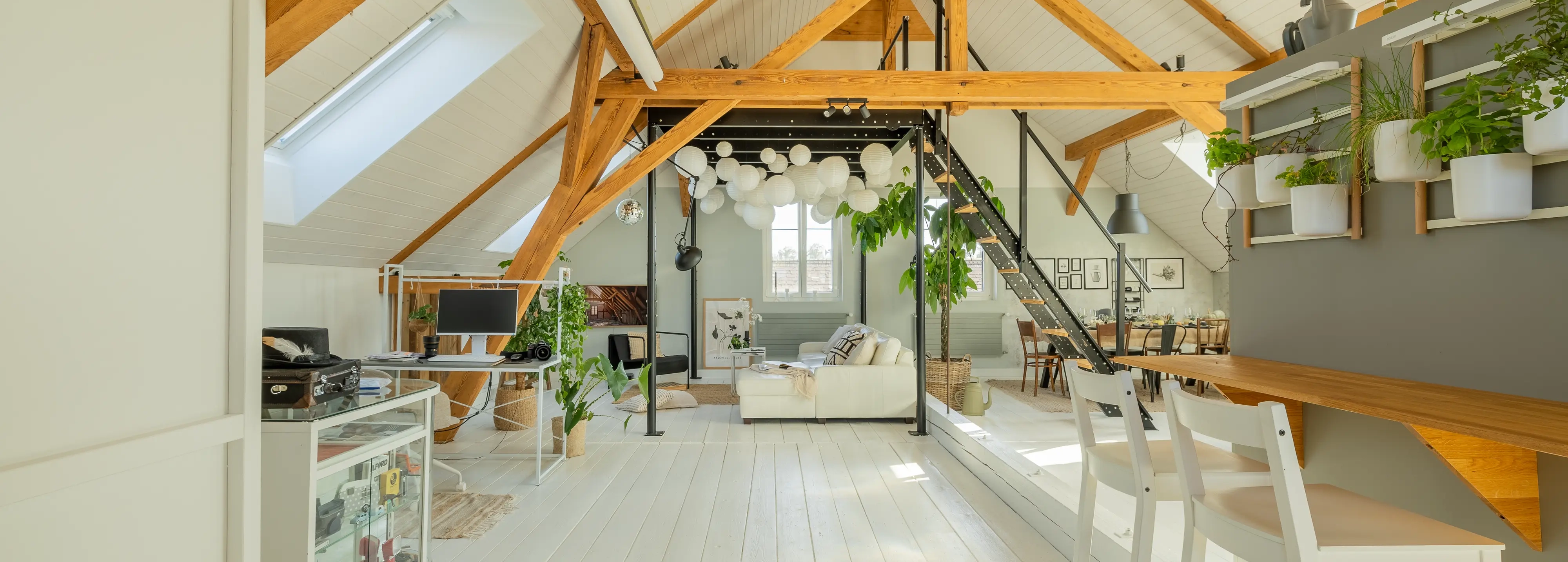 Spacious attic room with sloped ceiling, VELUX roof windows, and modern decor.